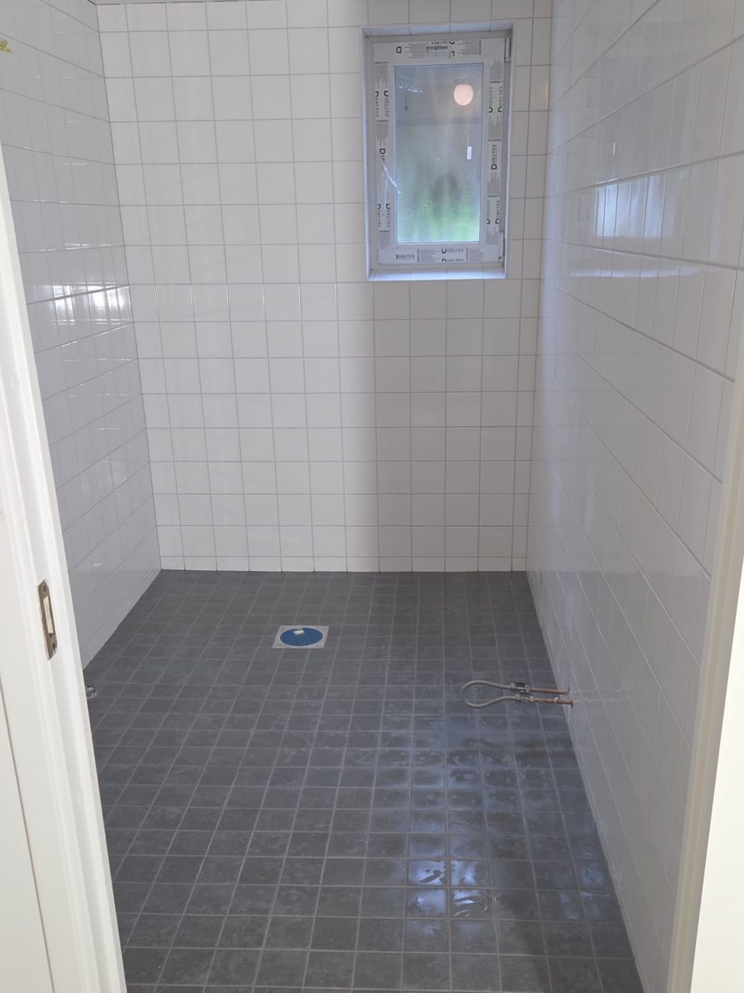 Badrum med mörkt golv i Hässelby, utfört av Stockholm Kakelkoncept & Bygg AB