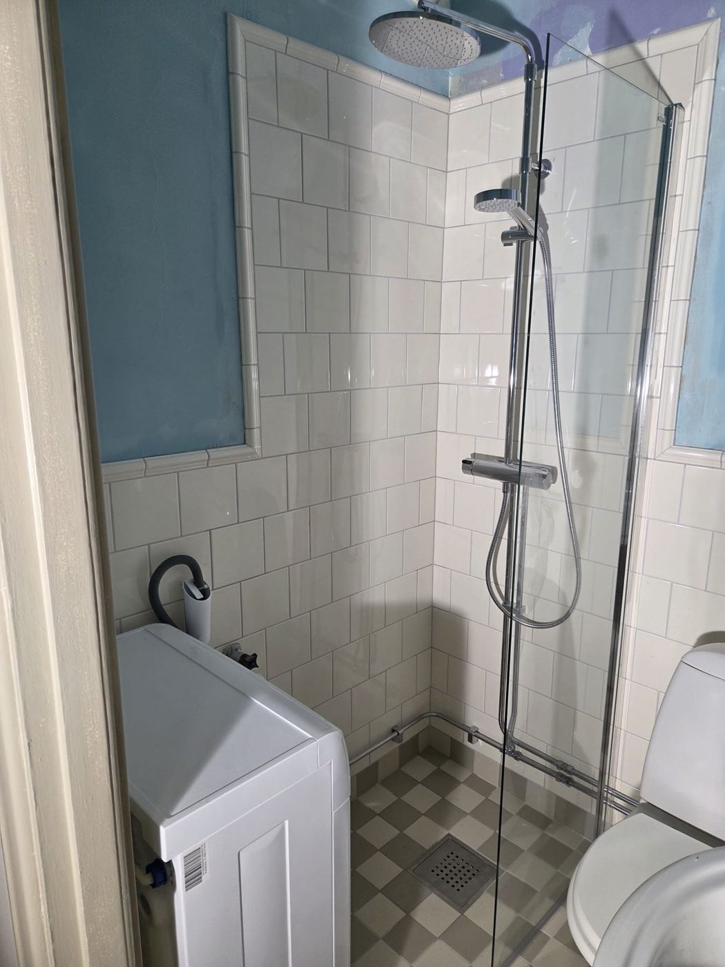 Badrum med vit vägg och mönstrat golv i Östermalm, utfört av Stockholm Kakelkoncept & Bygg AB