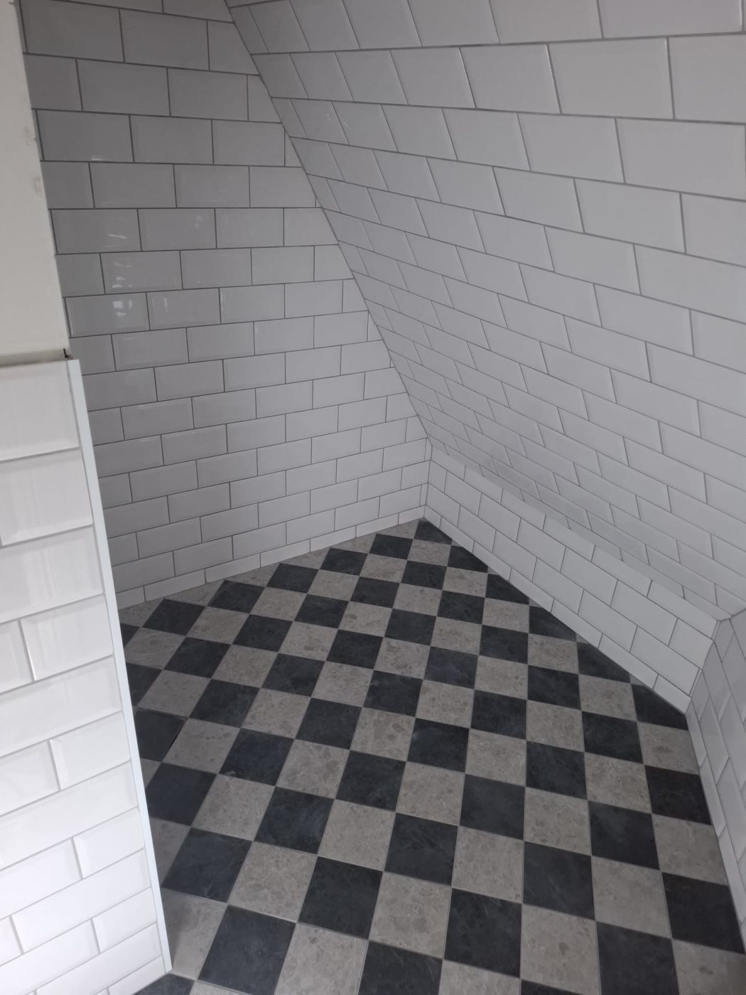Schackrutigt golv under snedtak i Norrmalm, utfört av Stockholm Kakelkoncept & Bygg AB